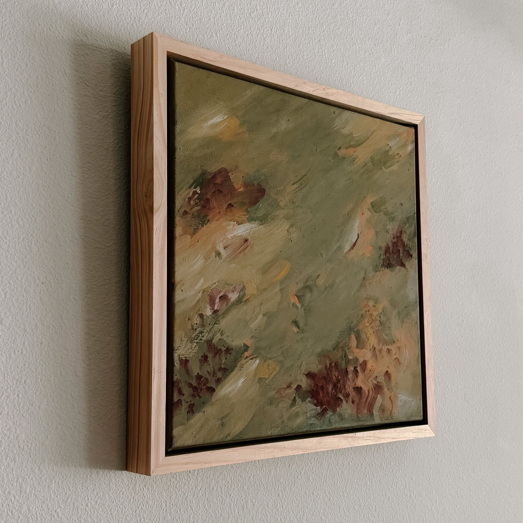 Framed abstract painting on a plain wall