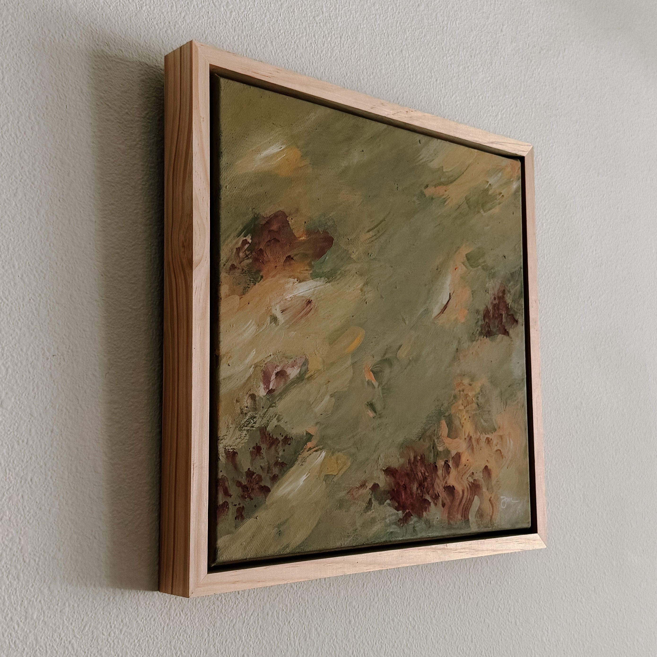 Framed abstract painting on a plain wall