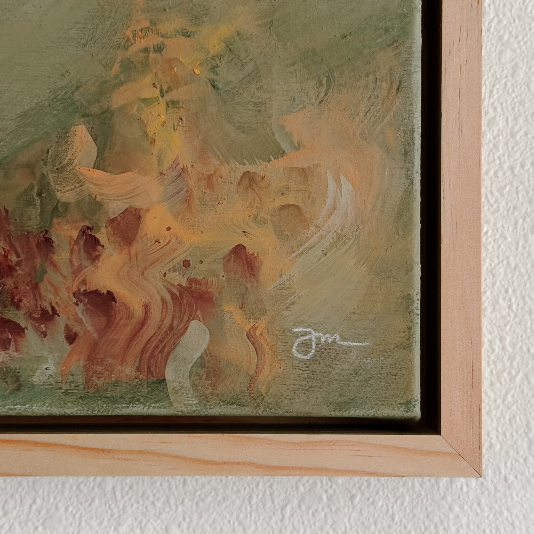 Abstract painting with a signature in a wooden frame on a textured wall.